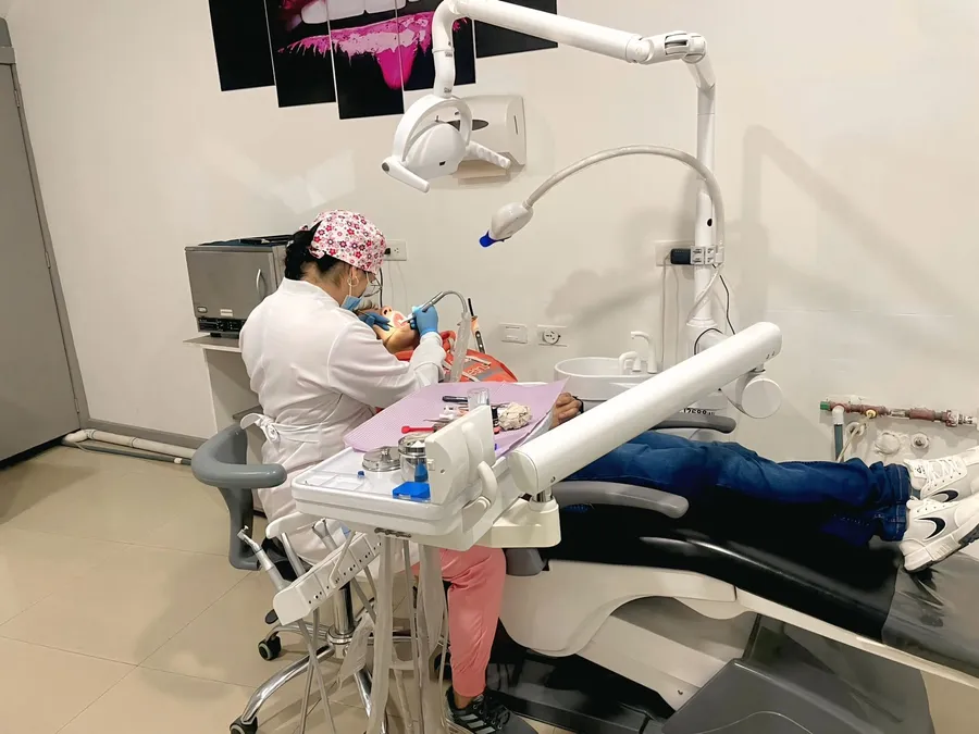 La Od. Cindy Moreira atiende a un paciente recostado en el sillón de su consultorio odontológico en Cuenca