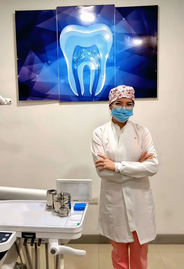 La Od. Cindy Moreira, con bata blanca y mascarilla, de pie en su consultorio odontológico de Cuenca