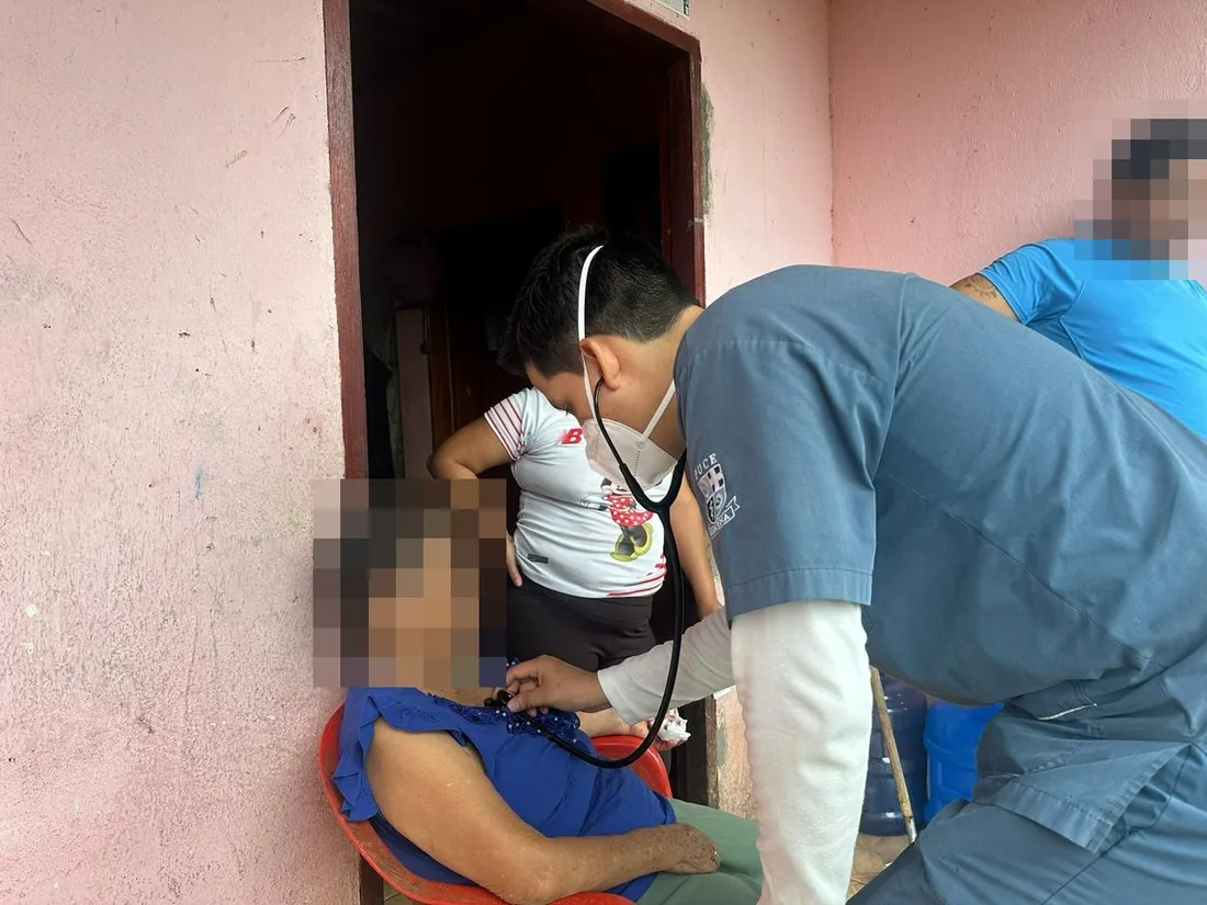 Un médico de CrabCare ausculta a un paciente adulto mayor sentado en su domicilio, en Quito