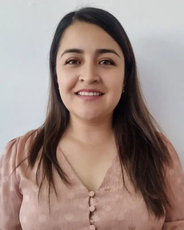 Retrato de la Dra. Lizzeth Quezada sonriendo, frente a una pared clara
