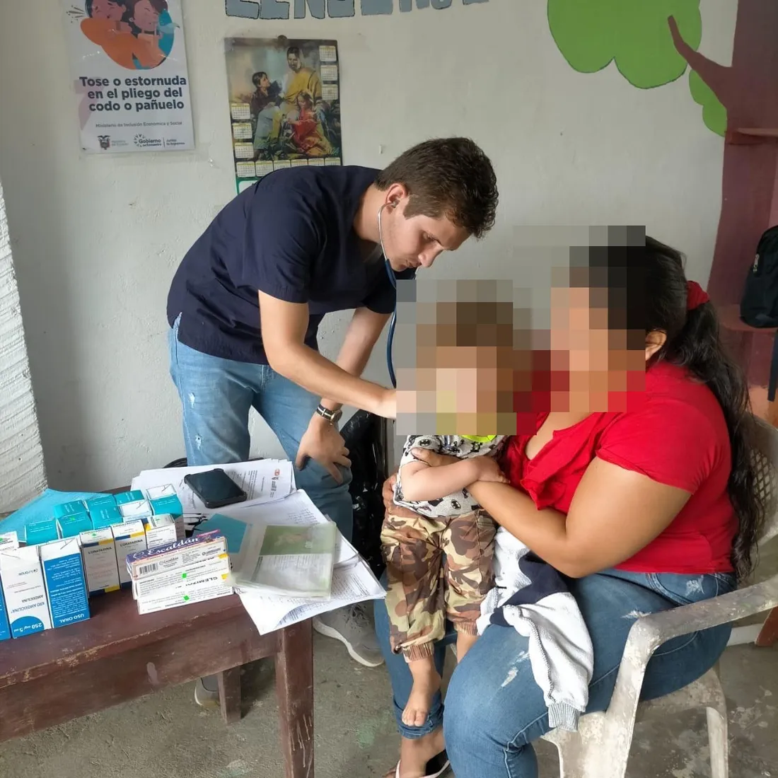 Un médico de CrabCare ausculta a un niño pequeño en brazos de su madre, durante una atención a domicilio en Quito